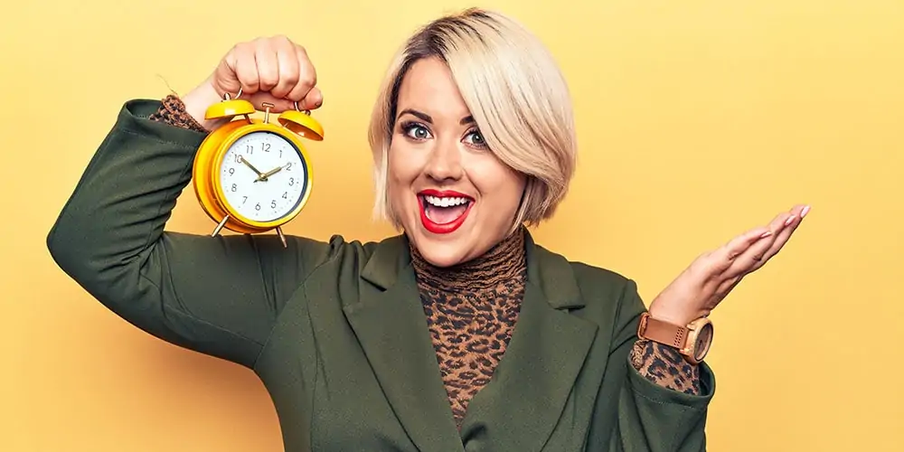 Smiling blonde woman holding clock